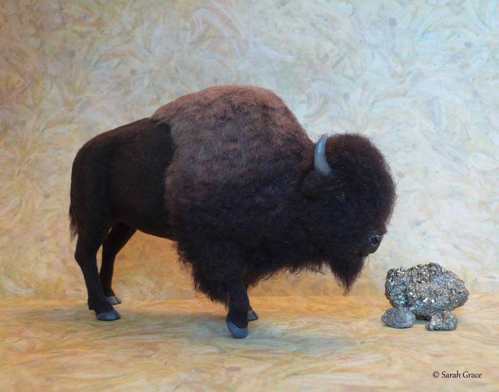 Impressive realistic miniature bison sculpture standing among rocks with textured horns and shaggy fur by Sarah Grace
