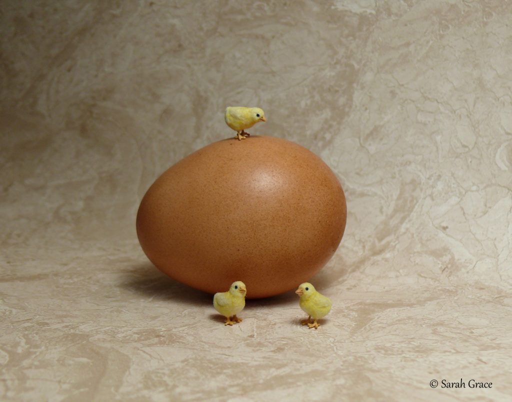 Cute realistic miniature yellow chicks sculpture gathered around an egg with fluffy details by Sarah Grace