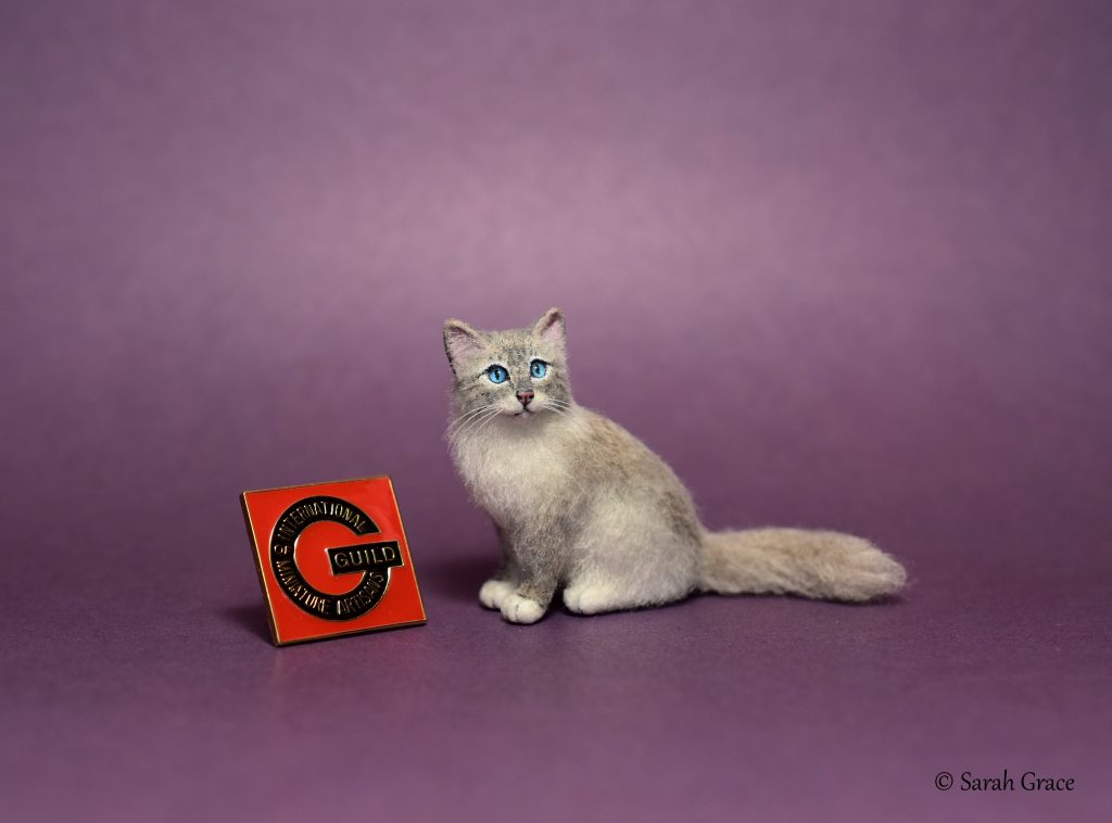 Detailed handmade miniature Ragdoll cat sculpture featuring fluffy fur, blue eyes, and a gentle seated pose by Sarah Grace