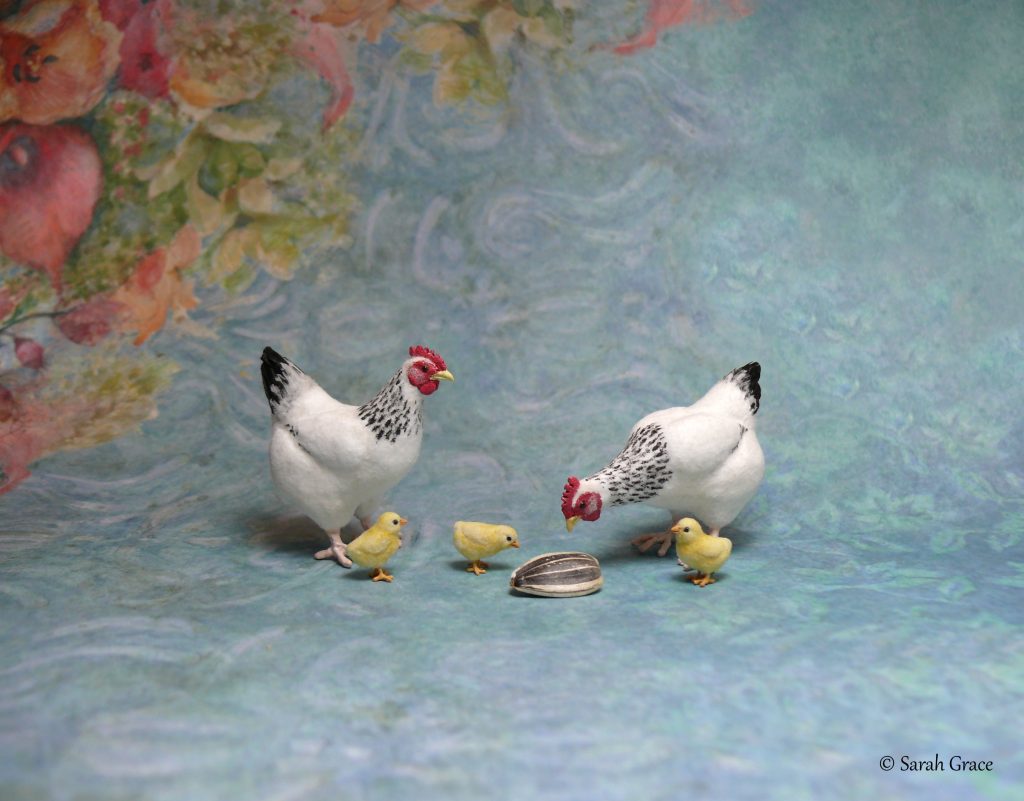 Detailed 1:12 scale miniature sculptures of hens with their chicks pecking at a sunflower seed by Sarah Grace