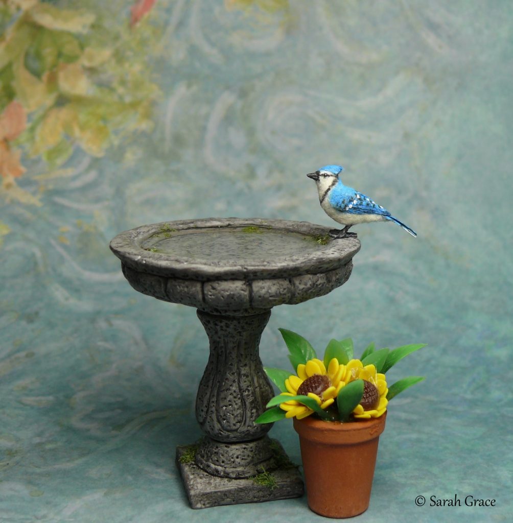 1:12 scale miniature blue jay sculpture sitting at a birdbath by Sarah Grace